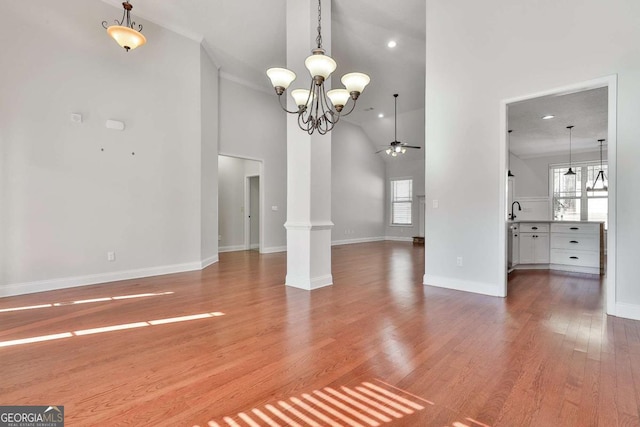 interior space featuring hardwood / wood-style floors, high vaulted ceiling, and ceiling fan with notable chandelier