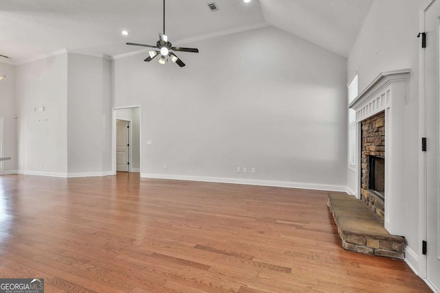 unfurnished living room with vaulted ceiling, light hardwood / wood-style floors, crown molding, ceiling fan, and a stone fireplace