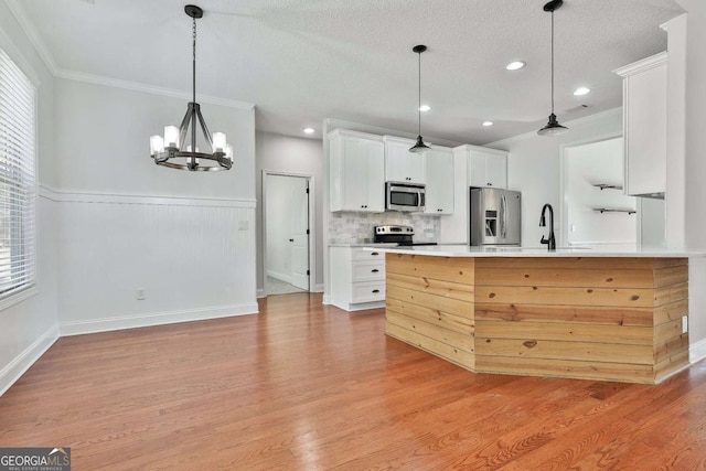 kitchen featuring light hardwood / wood-style flooring, hanging light fixtures, an inviting chandelier, white cabinets, and appliances with stainless steel finishes