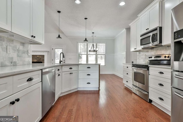 kitchen with stainless steel appliances, white cabinets, a textured ceiling, decorative backsplash, and pendant lighting