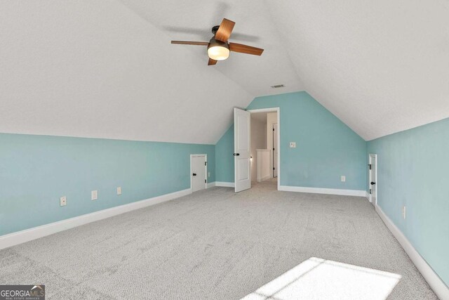 bonus room with vaulted ceiling, a textured ceiling, ceiling fan, and carpet