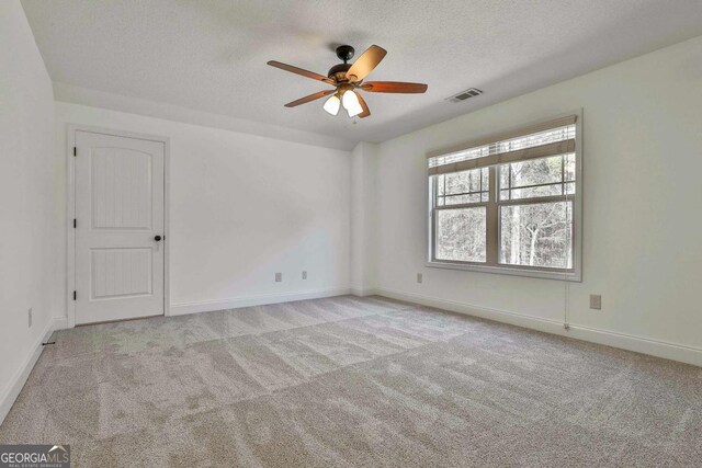 spare room featuring a textured ceiling, ceiling fan, and light colored carpet