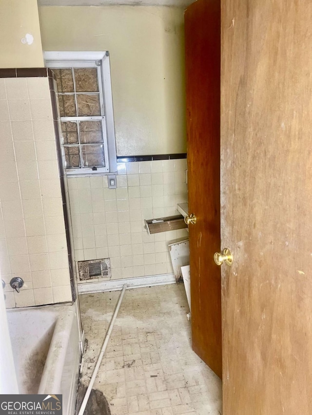 bathroom featuring a washtub and tile walls