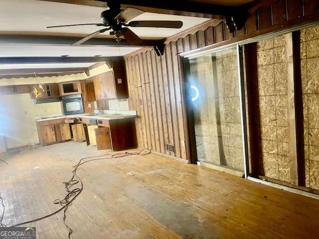 kitchen featuring ceiling fan, light wood-type flooring, beamed ceiling, and black oven