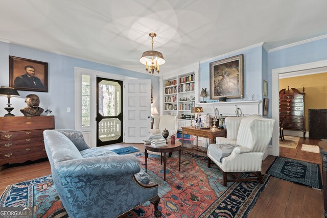 living room with an inviting chandelier, crown molding, built in shelves, and hardwood / wood-style flooring