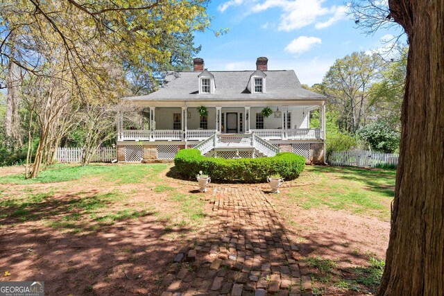 back of house featuring covered porch and a yard