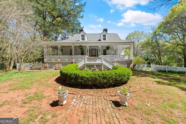 back of house with covered porch and a lawn