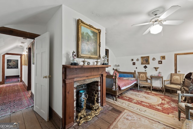 living area featuring ceiling fan, hardwood / wood-style floors, lofted ceiling with beams, and a fireplace