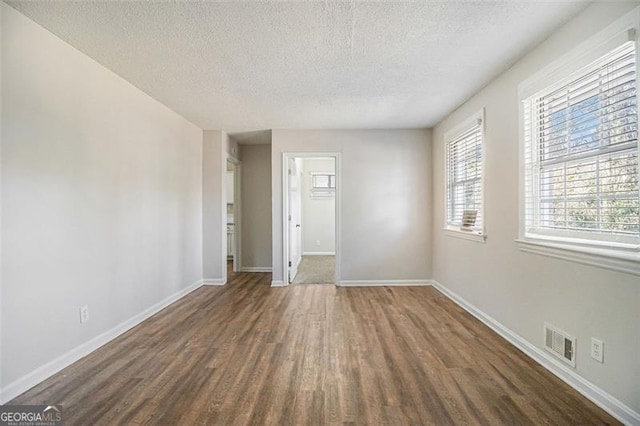 empty room with a textured ceiling and dark hardwood / wood-style flooring