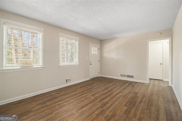 unfurnished room with a textured ceiling and dark hardwood / wood-style floors