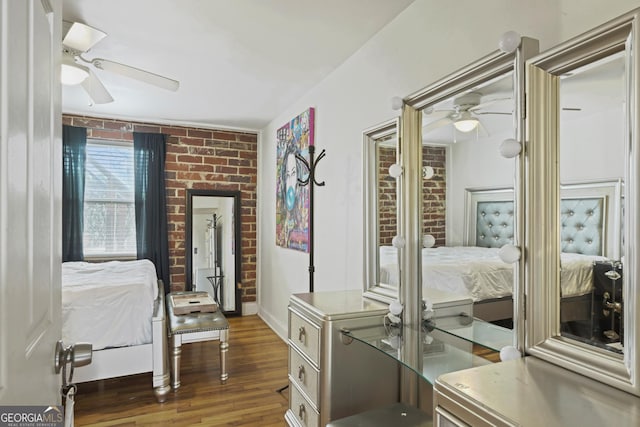 bedroom with dark wood-type flooring, ceiling fan, and brick wall