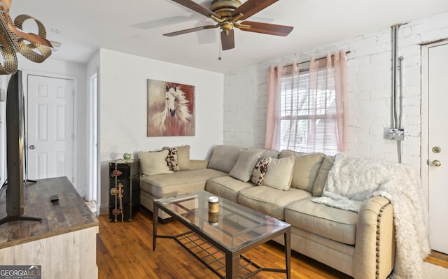 living room featuring ceiling fan, brick wall, and hardwood / wood-style floors