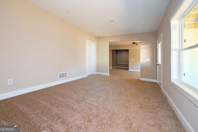 carpeted empty room with a ceiling fan, visible vents, and baseboards