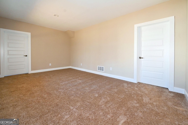 empty room featuring carpet, visible vents, and baseboards