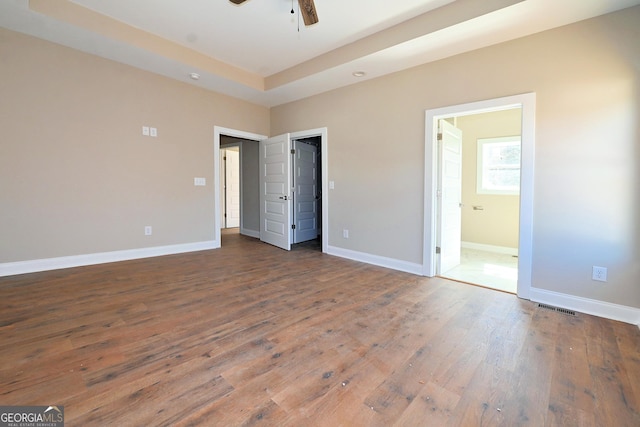 unfurnished bedroom with connected bathroom, a ceiling fan, visible vents, baseboards, and wood-type flooring