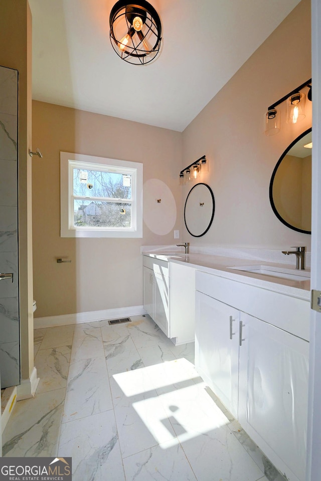 bathroom with marble finish floor, double vanity, visible vents, a sink, and baseboards