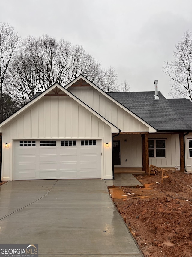 view of front of home featuring an attached garage, concrete driveway, board and batten siding, and roof with shingles