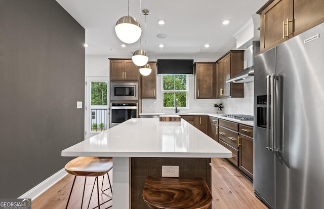 kitchen featuring a kitchen island, backsplash, hanging light fixtures, and appliances with stainless steel finishes