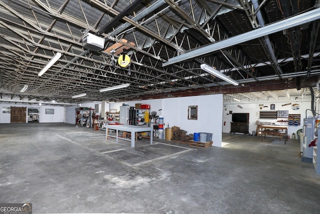 garage featuring a garage door opener, electric water heater, and a workshop area