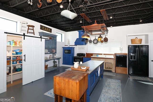 kitchen featuring blue cabinets, a barn door, black appliances, and hanging light fixtures