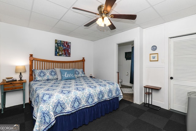 bedroom with ceiling fan, a closet, and a drop ceiling