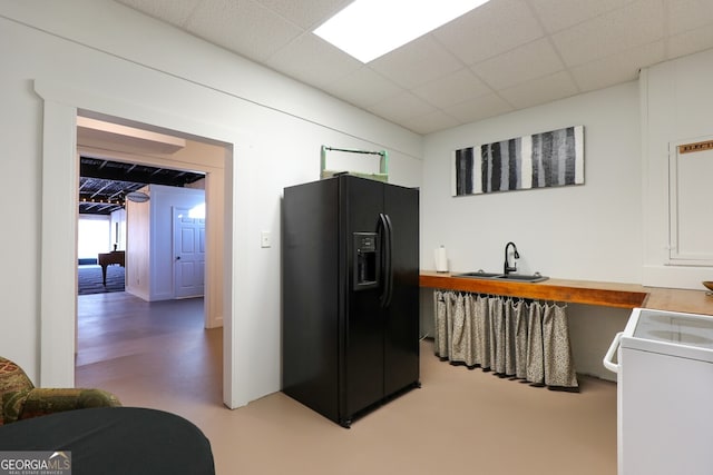 kitchen featuring sink, a drop ceiling, black refrigerator with ice dispenser, and range