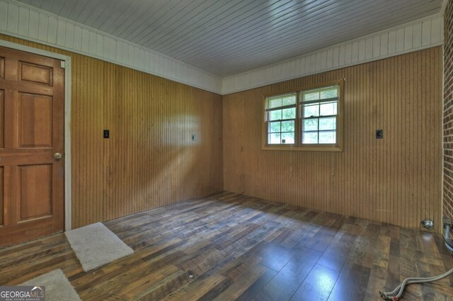 empty room with wood walls and dark hardwood / wood-style flooring