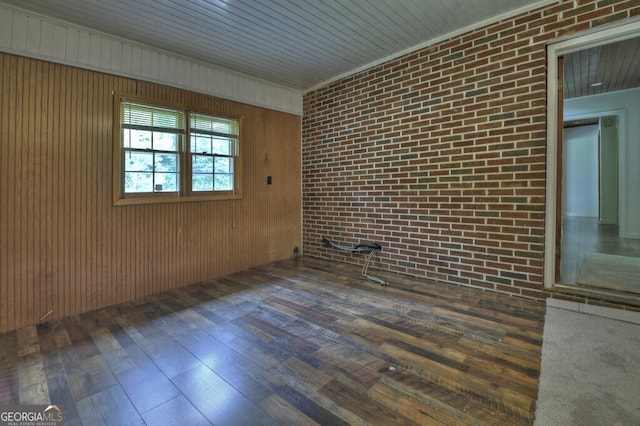 interior space featuring brick wall, wooden walls, and dark hardwood / wood-style floors