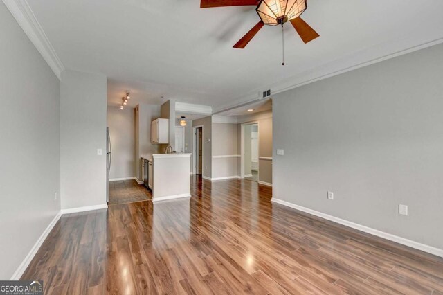 unfurnished living room featuring ceiling fan, dark hardwood / wood-style floors, and ornamental molding