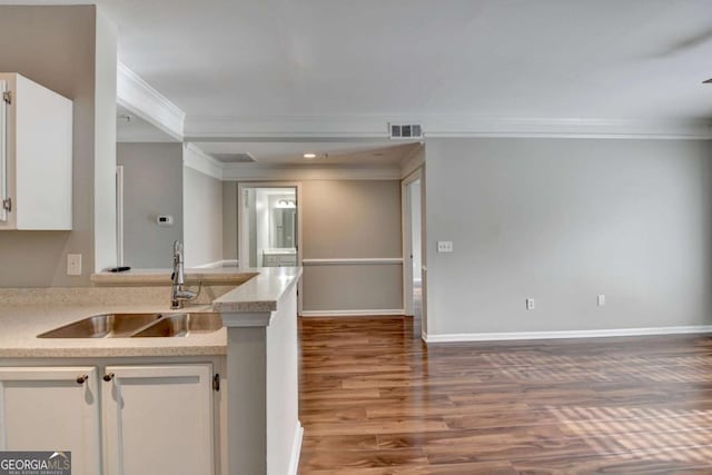 kitchen featuring sink, white cabinetry, ornamental molding, and hardwood / wood-style floors