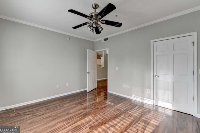 unfurnished bedroom featuring ceiling fan, dark wood-type flooring, and crown molding