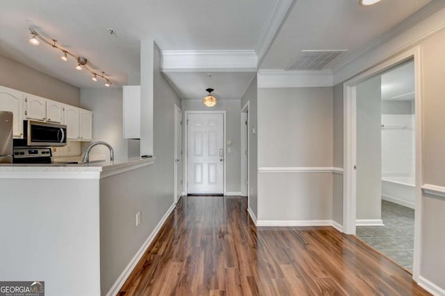 kitchen with white cabinets, appliances with stainless steel finishes, decorative backsplash, sink, and crown molding