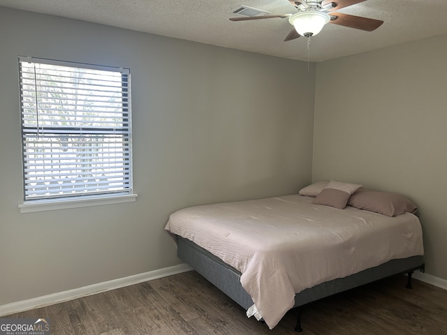 bedroom with a textured ceiling, ceiling fan, and dark hardwood / wood-style flooring