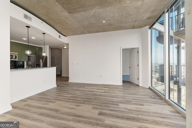 unfurnished living room with a wall of windows, hardwood / wood-style floors, and a wealth of natural light