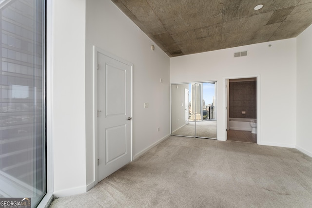 unfurnished bedroom featuring light colored carpet and connected bathroom