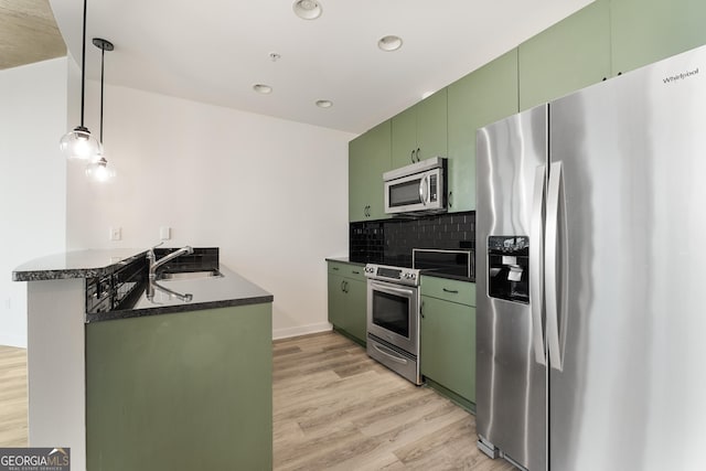 kitchen featuring kitchen peninsula, green cabinetry, tasteful backsplash, appliances with stainless steel finishes, and sink