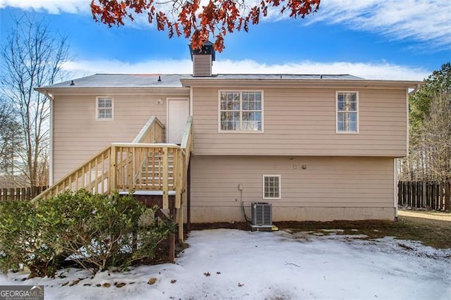 snow covered rear of property featuring central air condition unit