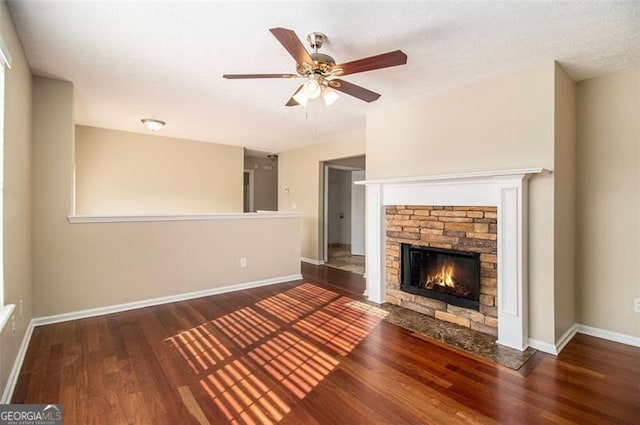 unfurnished living room featuring dark wood-type flooring, a textured ceiling, ceiling fan, and a fireplace