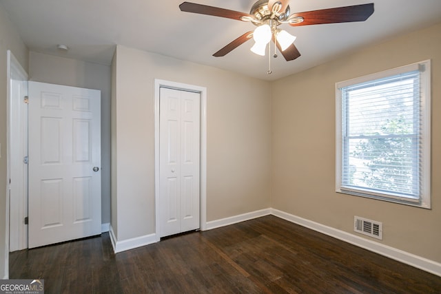 unfurnished bedroom with dark hardwood / wood-style flooring, ceiling fan, and a closet