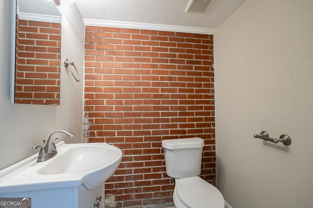 bathroom with vanity, brick wall, and toilet