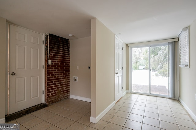 foyer featuring brick wall and light tile patterned floors