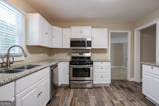 kitchen featuring light stone counters, dark hardwood / wood-style floors, stainless steel appliances, white cabinets, and sink