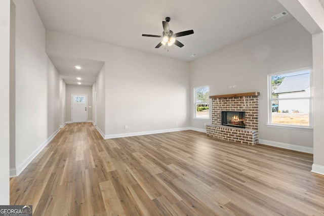 unfurnished living room with ceiling fan, light hardwood / wood-style flooring, and a fireplace