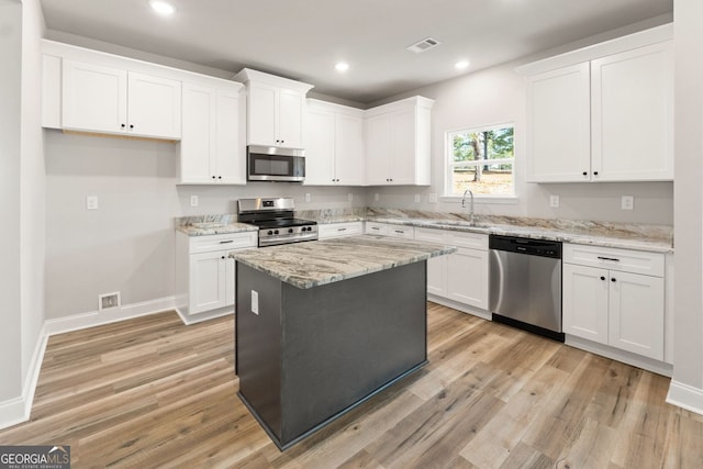 kitchen with light stone countertops, white cabinets, a center island, and stainless steel appliances