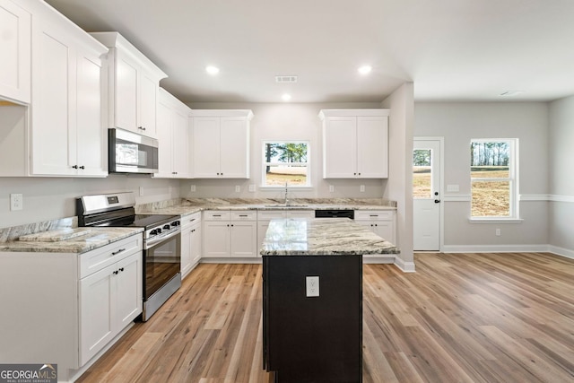 kitchen with white cabinetry, appliances with stainless steel finishes, light wood-type flooring, light stone counters, and a center island