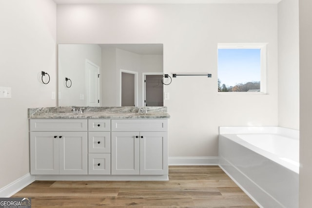 bathroom with a bathing tub, hardwood / wood-style flooring, and vanity