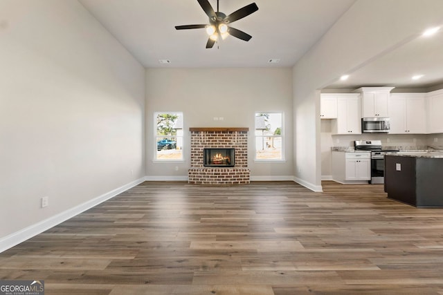 unfurnished living room with dark wood-type flooring, a fireplace, and ceiling fan