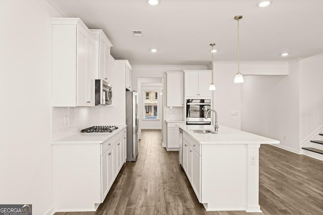 kitchen featuring a kitchen island with sink, white cabinets, and appliances with stainless steel finishes