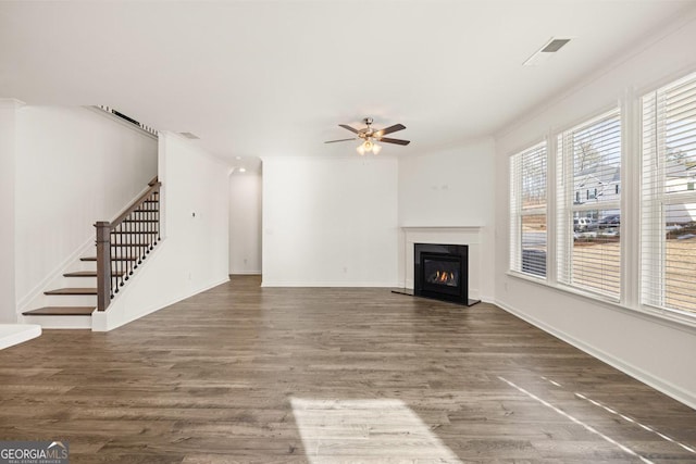 unfurnished living room with dark hardwood / wood-style flooring, ornamental molding, and ceiling fan