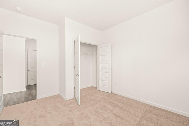 unfurnished bedroom with light colored carpet and a closet